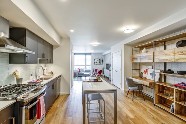 Modern kitchen with dark cabinets, stainless steel appliances, and island at Radius Apartments in a luxury environment