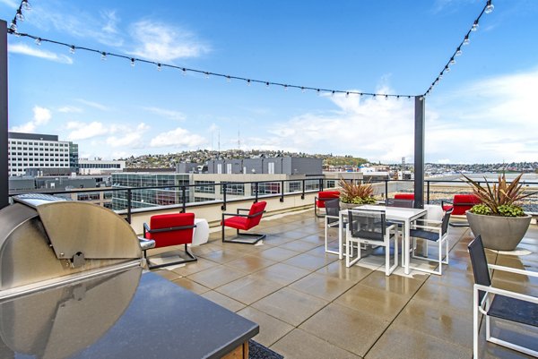 Rooftop patio with grill and seating overlooking cityscape at Radius Apartments