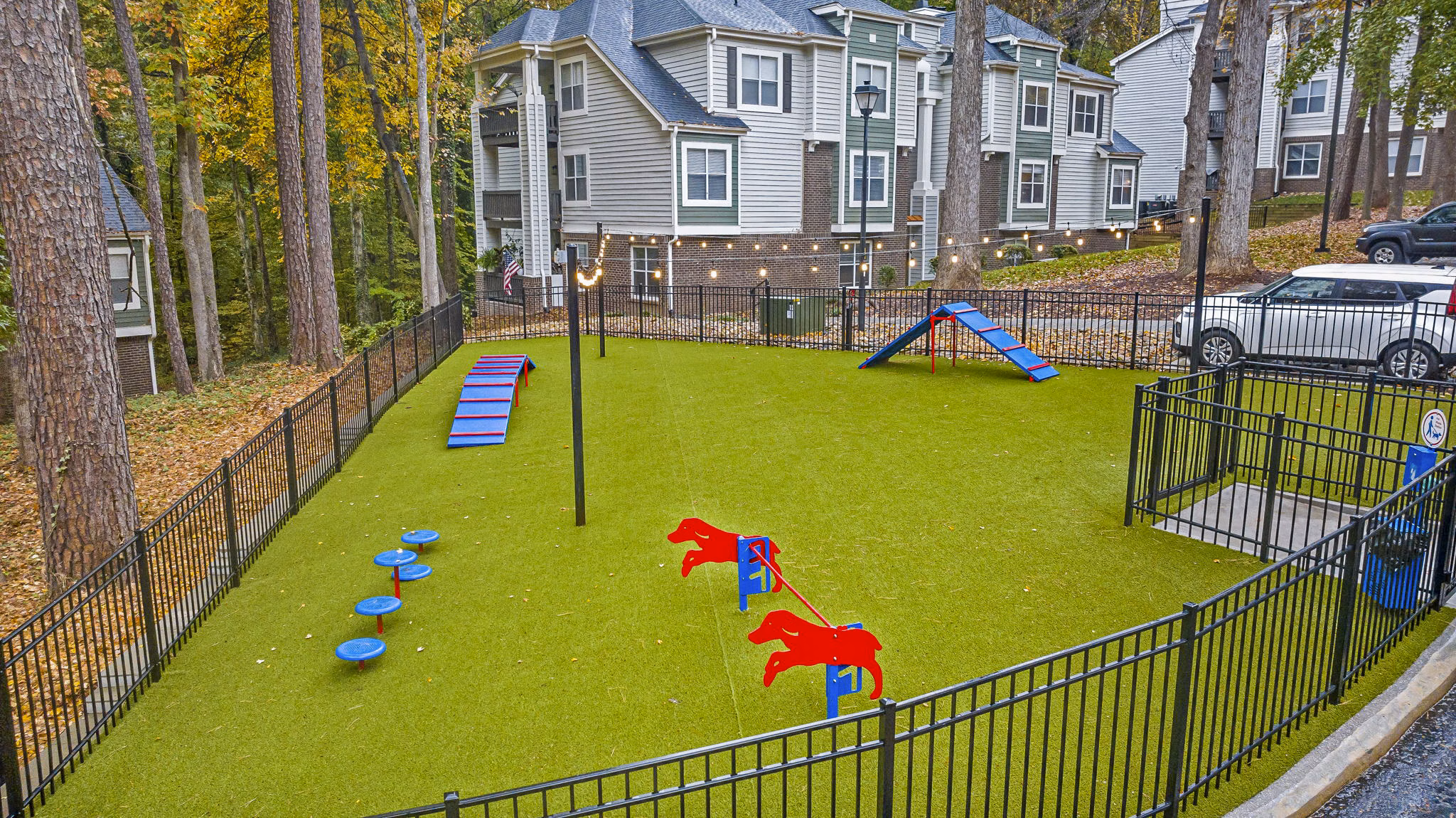 Dog park area with green space and agility equipment at Harvest Apartments, ideal for pet-friendly outdoor activities and community interaction