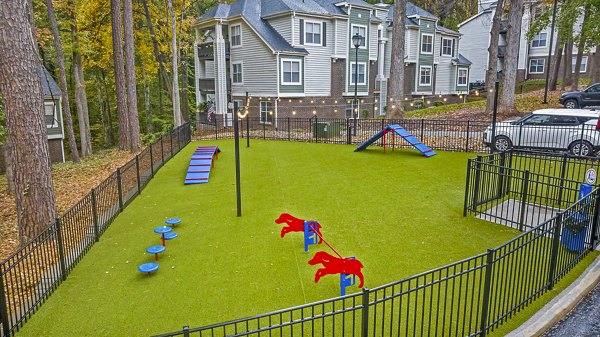 Dog park area with green space and agility equipment at Harvest Apartments, ideal for pet-friendly outdoor activities and community interaction