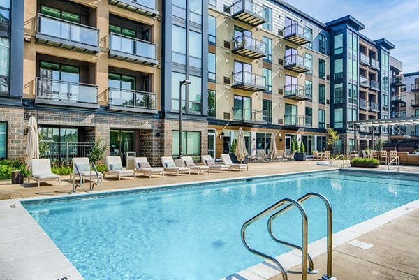 Vibrant pool area with lounge chairs at The Island Residences at Carlson Center Apartments, offering relaxation and leisure for residents