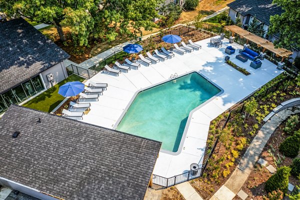 Crystal-clear pool with lounge chairs at The Alden Apartments