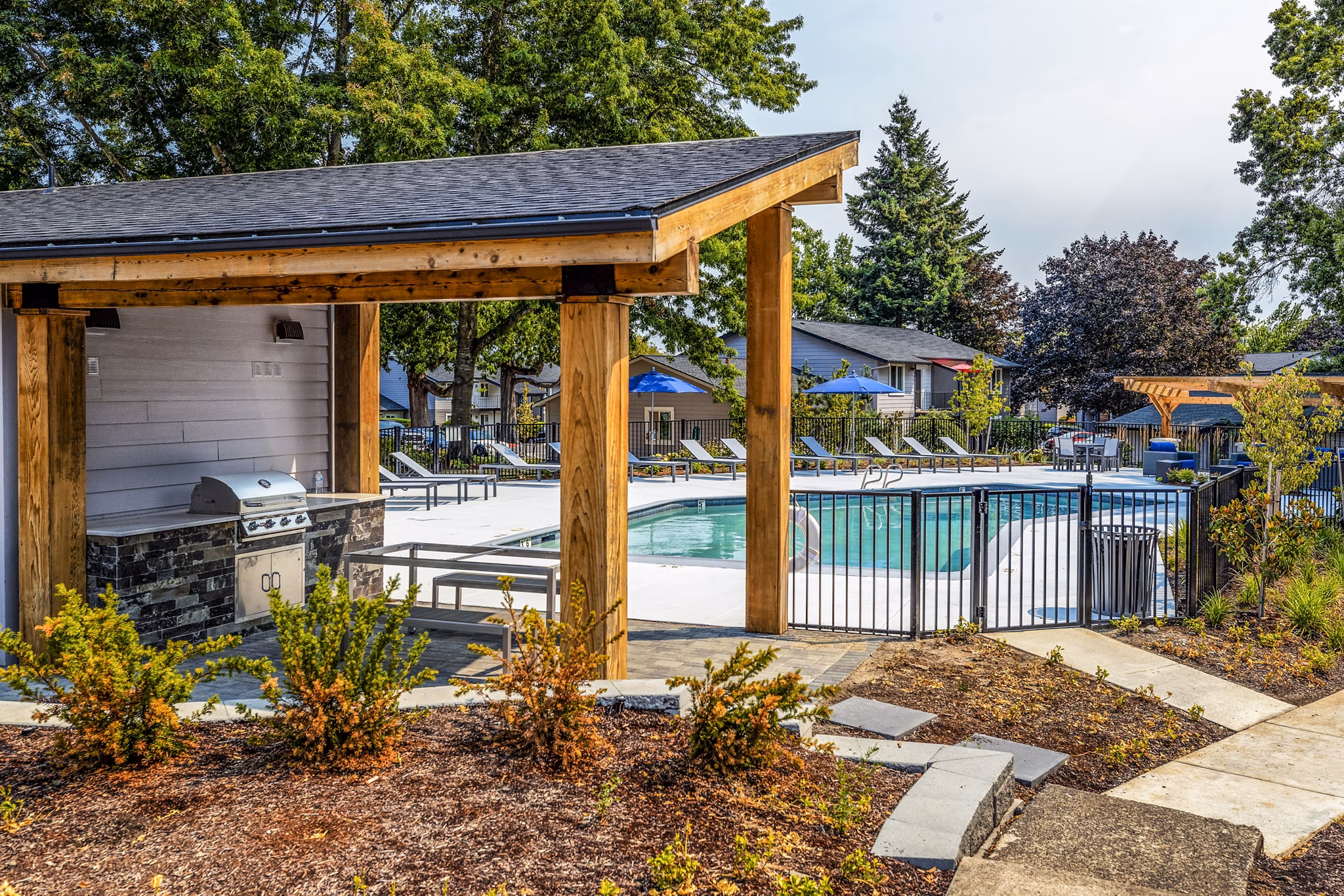 Grill area beside a shimmering pool at The Alden Apartments, perfect for outdoor gatherings and relaxation