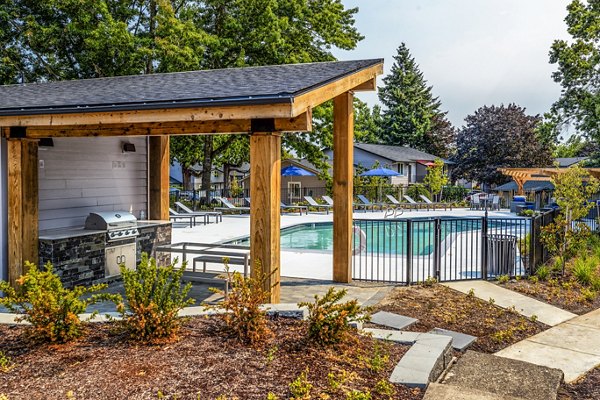 Grill area beside a shimmering pool at The Alden Apartments, perfect for outdoor gatherings and relaxation