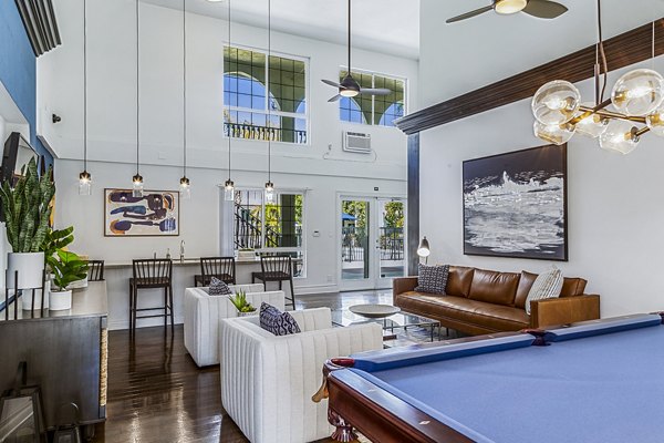 Game room with billiards and lounging area at Madrid Apartments clubhouse
