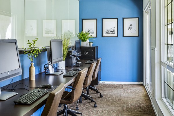 Modern business center with sleek workstations at Madrid Apartments offering a productive space for residents
