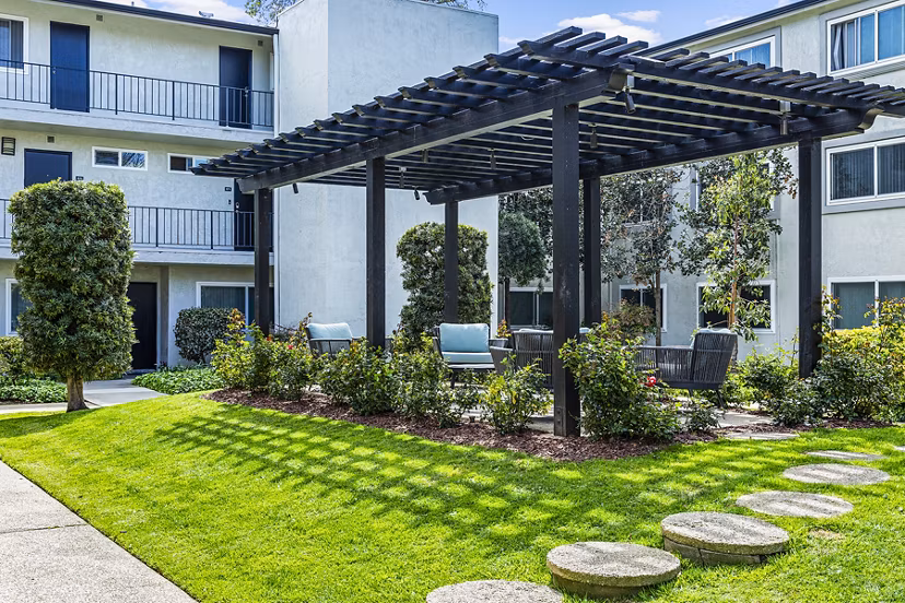 Clubhouse patio with modern seating and lush greenery at Madrid Apartments
