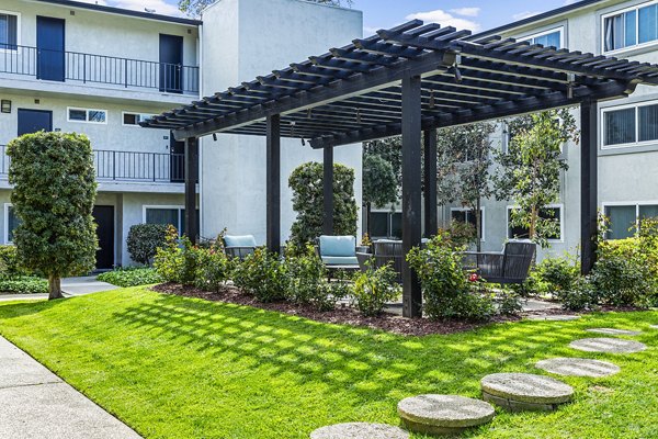 Clubhouse patio with modern seating and lush greenery at Madrid Apartments