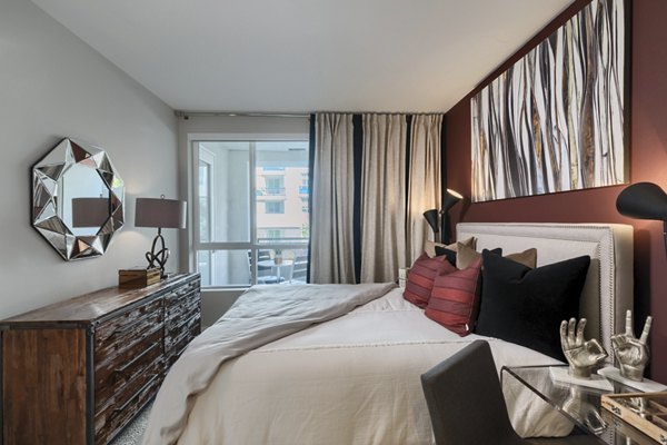 Spacious bedroom with modern decor in Altana Apartments, featuring large windows and neutral tones