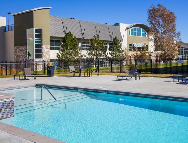 Swimming pool area with red Adirondack chairs next to a luxury apartment building