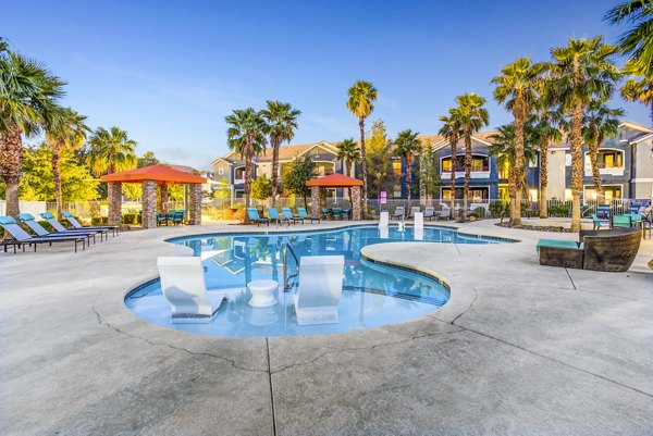 Relaxing pool area with lounge chairs and palm trees at Tesoro Ranch Apartments