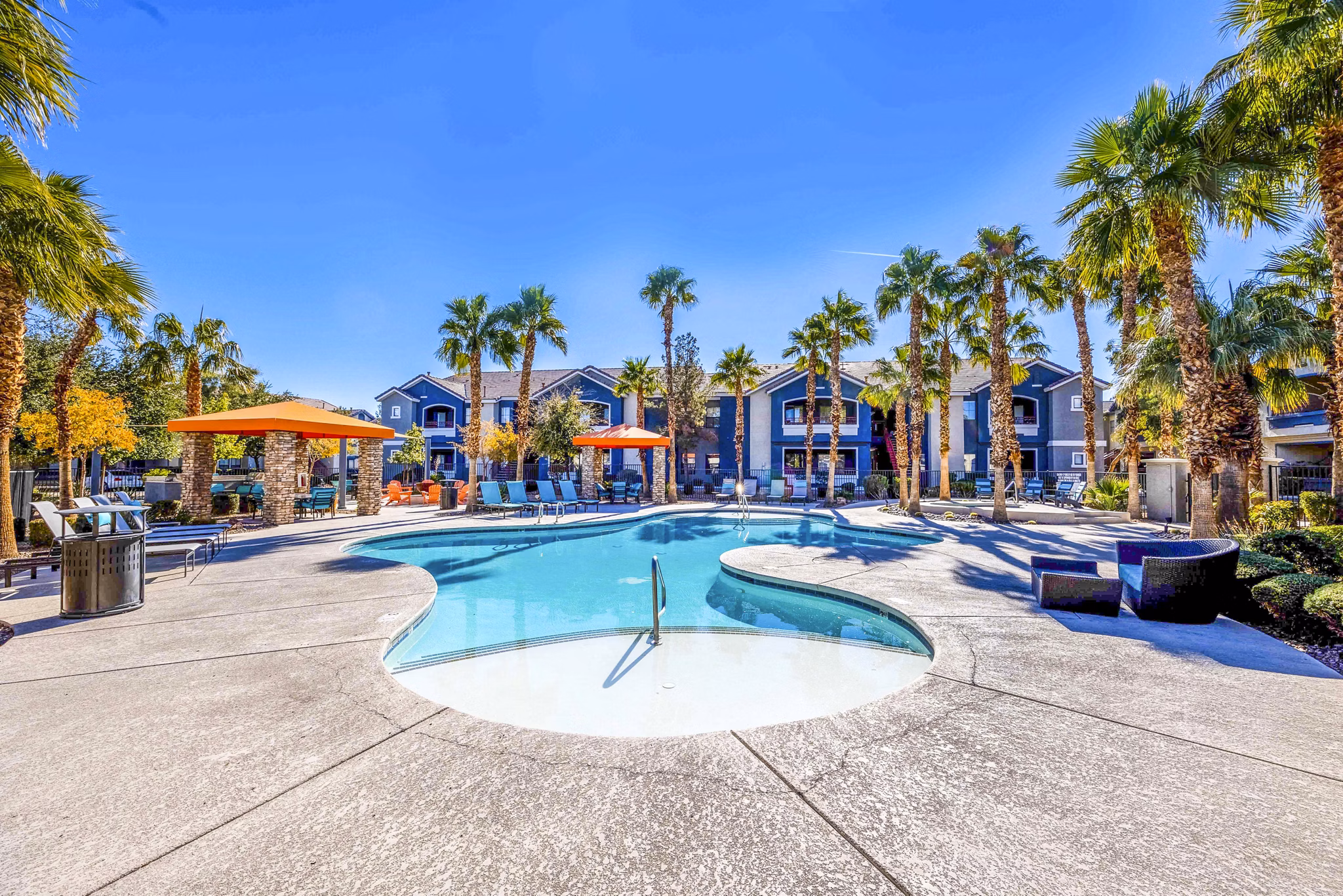 Resort-style pool with palm trees at Tesoro Ranch Apartments offering luxury living in a serene environment