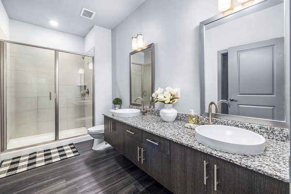Luxury bathroom featuring sleek fixtures and large mirror at District Lofts Apartments