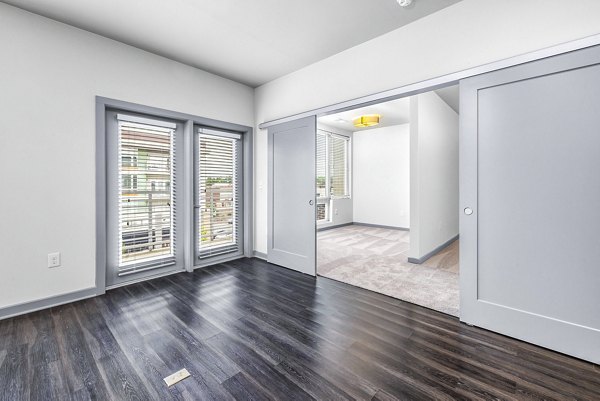 Spacious living room with modern decor and large windows at District Lofts Apartments, offering luxurious living in a vibrant community