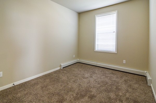 Cozy bedroom with plush bedding and natural light in South Ridge Apartments