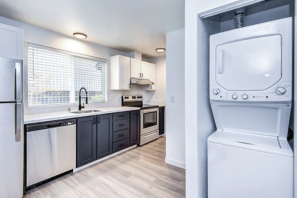 Laundry room and kitchen with modern appliances at Park 120 Apartments