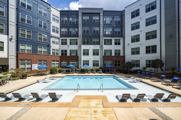 Sunlit outdoor pool at 1133 on the Square Apartments, featuring spacious deck and lush landscaping in vibrant city setting