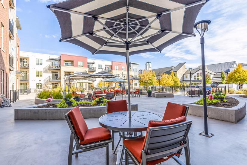 Patio with lush garden view at Overture Central Park Apartments, perfect for outdoor relaxation and dining
