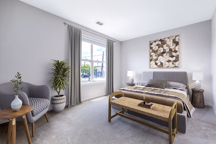 Cozy bedroom with modern decor at Rutherford Station Apartments, featuring a plush bed and stylish furnishings