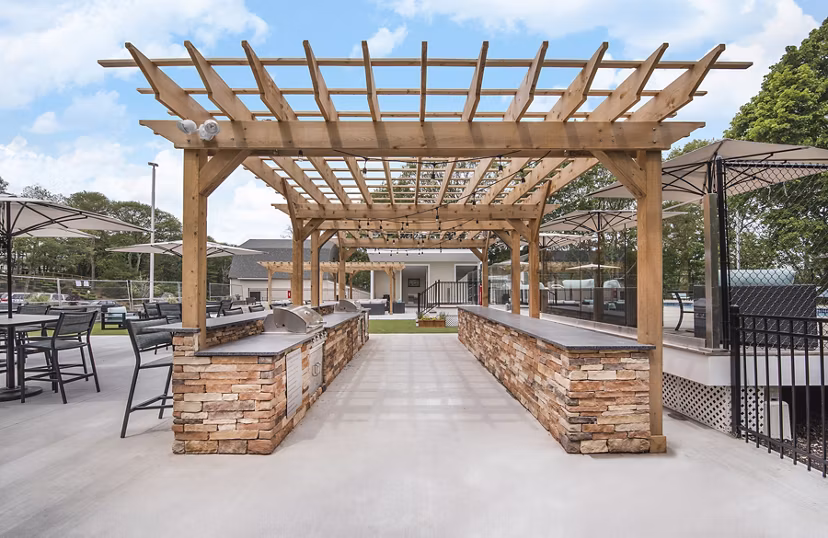 Outdoor BBQ grill area with modern seating at Avana Weymouth Apartments