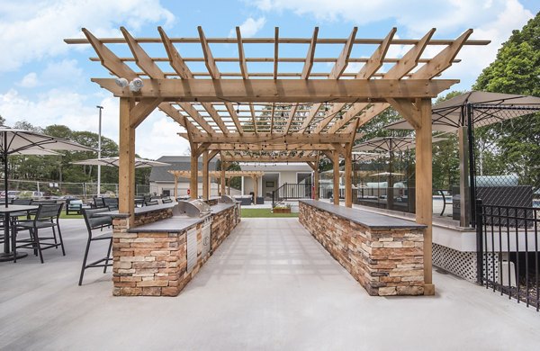 Outdoor BBQ grill area with modern seating at Avana Weymouth Apartments