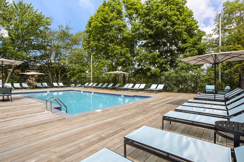 Spacious outdoor pool at Avana Weymouth Apartments with loungers and landscaped surroundings, perfect for relaxation