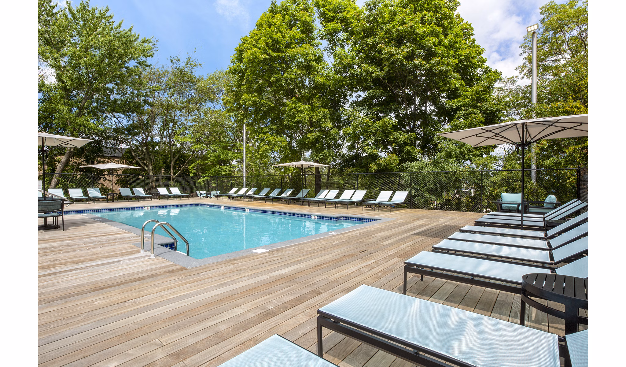Spacious outdoor pool at Avana Weymouth Apartments with loungers and landscaped surroundings, perfect for relaxation