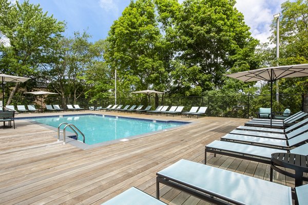 Spacious outdoor pool at Avana Weymouth Apartments with loungers and landscaped surroundings, perfect for relaxation