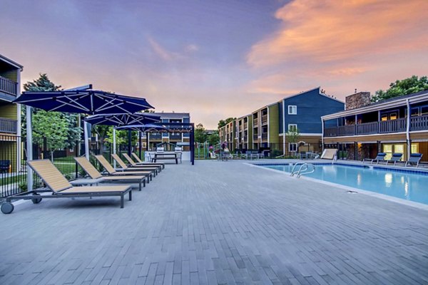 Spacious outdoor pool area at Park Place at 92nd Apartments with lounge chairs and landscaped surroundings