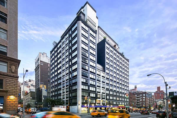 High-rise building on a busy city street with taxis at The Chelsea Apartments