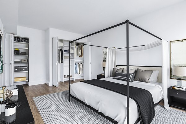 Minimalist bedroom with canopy bed, open closet, and neutral decor at The Chelsea Apartments