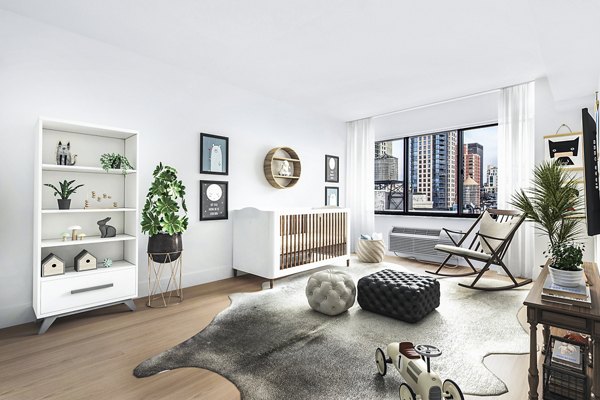 Modern nursery with city view, white furniture, and decor at The Chelsea Apartments