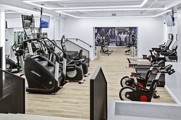 Spacious gym with various exercise machines and wooden flooring at The Chelsea Apartments