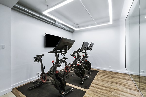 Three stationary bikes in a modern indoor cycling room at The Chelsea Apartments