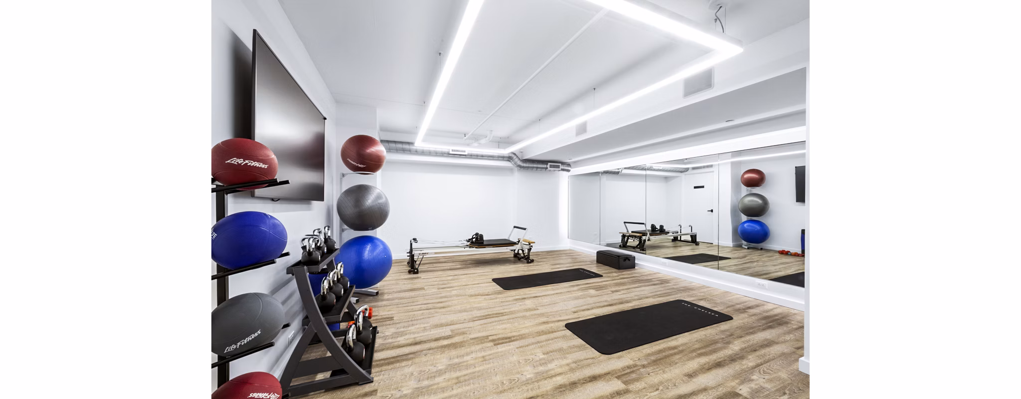 Well-equipped gym with exercise balls, weights, and rowing machines at The Chelsea Apartments