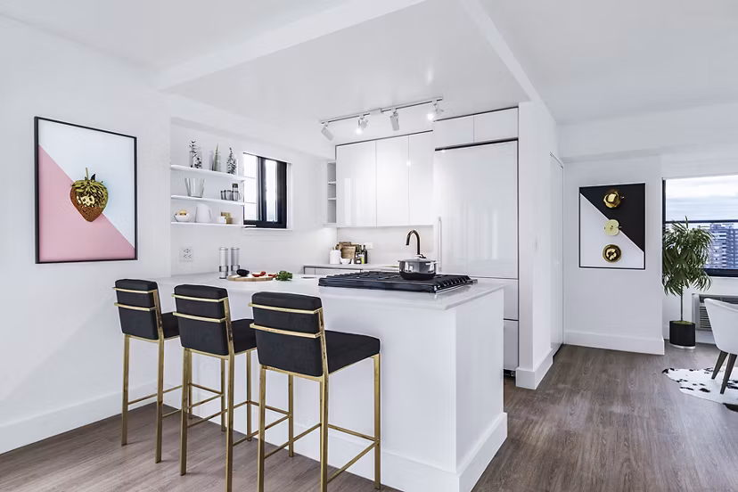 Sleek white kitchen with bar stools and wooden flooring at The Chelsea Apartments
