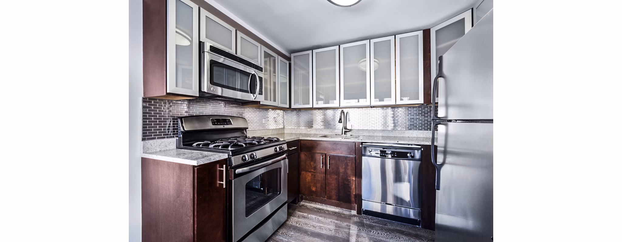 Sleek kitchen with stainless steel appliances and dark wood cabinets at The Chelsea Apartments