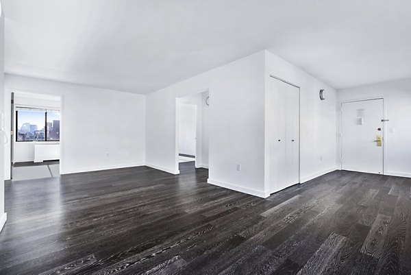 Spacious empty apartment with dark wood floors and white walls at The Chelsea Apartments