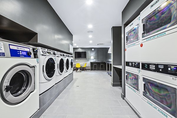 Bright laundry room with washers, dryers, and seating area at The Chelsea Apartments