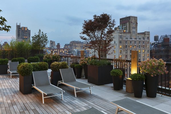 Rooftop terrace with lounge chairs and city skyline view at The Chelsea Apartments