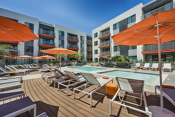 Luxury resort-style pool at The Tomscot Apartments with sunbathing area and lush landscaping