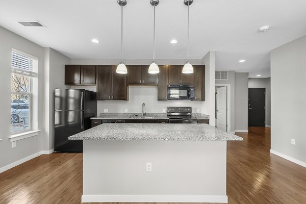 Modern kitchen featuring stainless steel appliances and granite countertops in Confluence at Three Springs Apartments