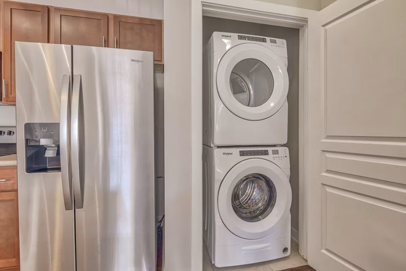 Laundry room with modern appliances and folding area in River Oaks Apartments
