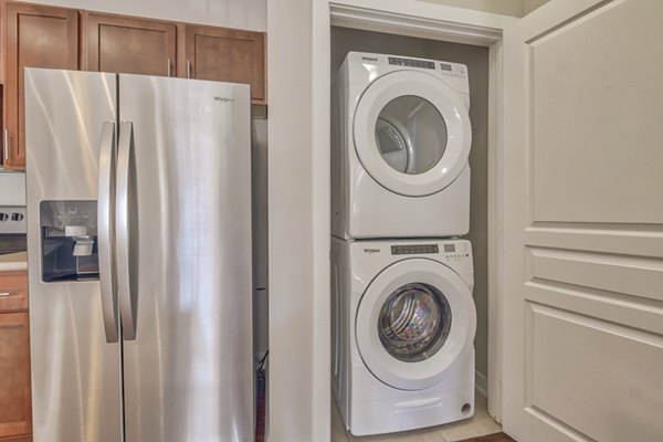 Laundry room with modern appliances and folding area in River Oaks Apartments