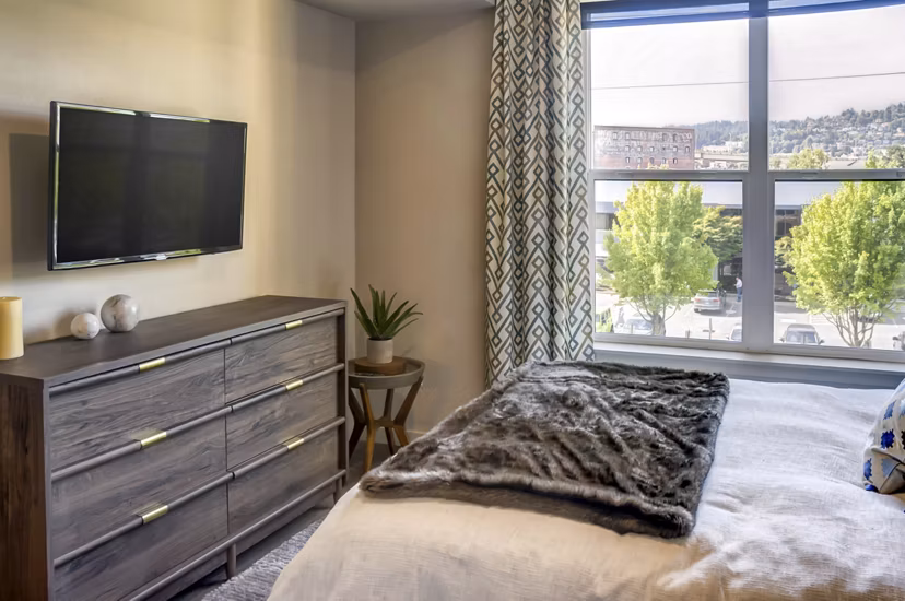Modern bedroom featuring large windows and contemporary decor at Waterline Apartments in Portland, OR.