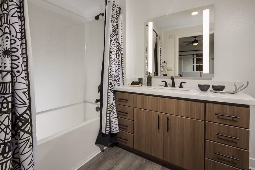 Modern bathroom with double vanity and marble countertops in Luxe Pasadena Apartments