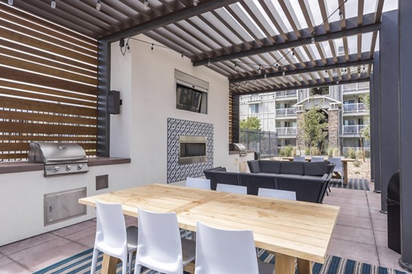 Outdoor grill area with shaded seating at Copperwood Apartments