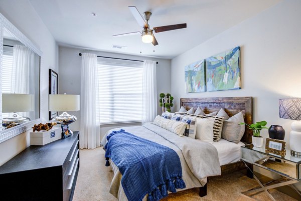 Bright bedroom with a large bed, ceiling fan, and decor at Platform Apartments offers comfort and style for luxury living