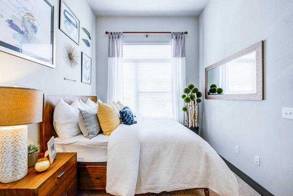 Bright bedroom with a wooden bed, white bedding, and wall art at Platform Apartments, showcasing modern luxury living tailored for comfort