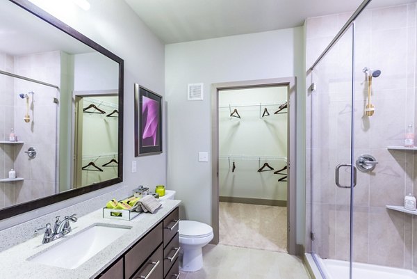 Platform Apartments: Spacious bathroom with double sink, glass shower, and walk-in closet in luxury Greystar apartment